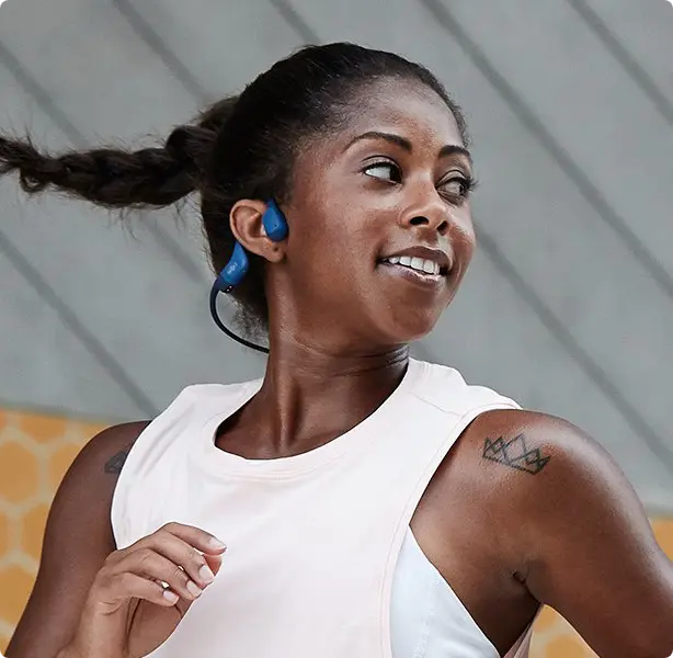 Corredora usando fone Shokz OpenRun de condução óssea ao ar livre